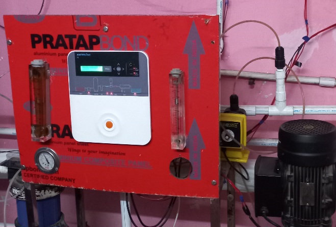 A close-up photo of a red industrial control panel with a monitor and a pump for wholesale mineral water 20 litre jar. The panel has buttons, knobs, and dials, and is labeled "PRATAP" and "RA phon CERTIFIED COMPANY".